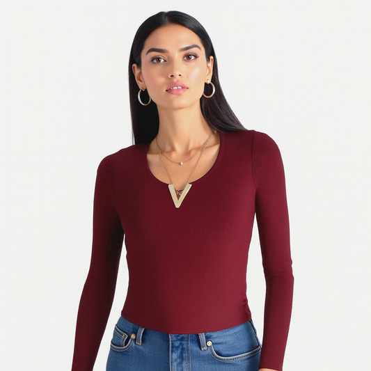 Woman wearing a burgundy long-sleeve top and blue jeans on a white background
