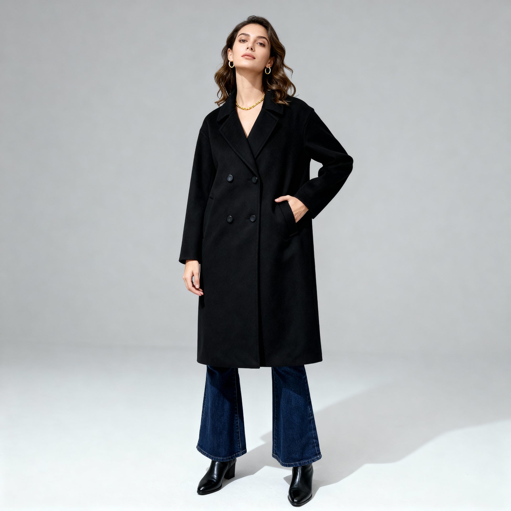 Woman wearing a black coat and blue jeans on a gray background